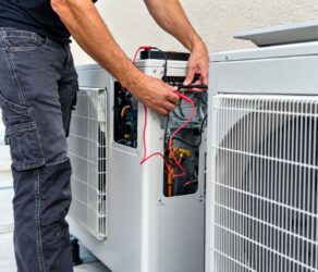 Professional technician performing residential heat pump installation on an outdoor unit.